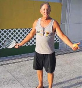 Stan-Reich-stands-in-front-of-his-homemade-driveway-pickleball-wall-280x300